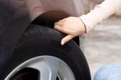 Woman's hand checking car tire pressure. The driver is checking the air pressure while traveling. 2162542583