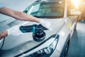 Car detailing - Man holds a polisher in the hand and polishes the car. Selective focus.