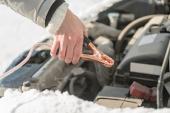 The car did not start because of the cold temperature. The woman connects the terminals to the battery. Day, winter, frost.