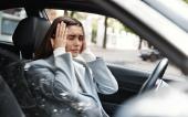 Woman having a panic attack in car. Businesswoman looking frustrated, sitting on driver seat, holding hands on head. Car accident and insurance concept.