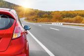 Red car on the side of the highway. Road trip.