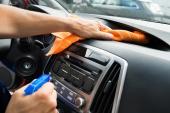 Cropped image of mature male worker cleaning car dashboard