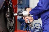 Close up of a motorcycle mechanic hands using a pneumatic gun to loosen a wheel nut in a mechanical workshop