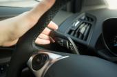 Closeup photo of woman driving car and using turn signal switch