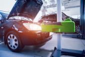 Worker checks and adjusts the headlights of a car's lighting system. Auto repair service.