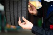 Mechanic checking checking the depth of car tire tread. Car maintenance and auto service garage concept.